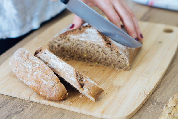 istock Young woman cutting freshly made bread 694834880