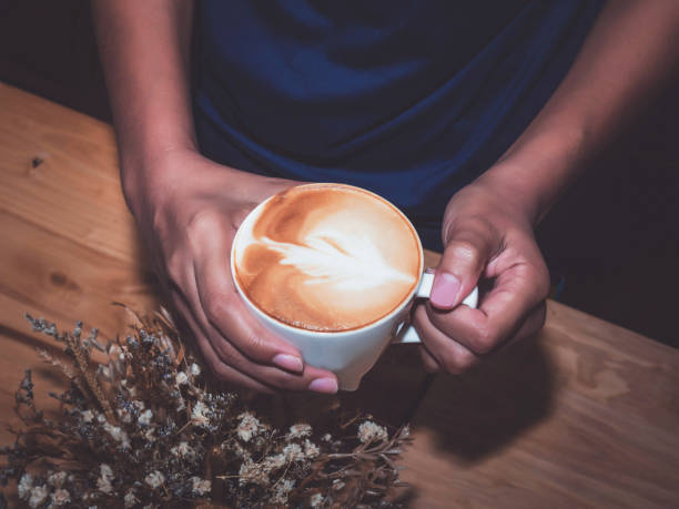 Latte art Female hands holding a cup of coffee. Latte art Female hands holding a cup of coffee on wooden table. mormon woman photos stock pictures, royalty-free photos & images