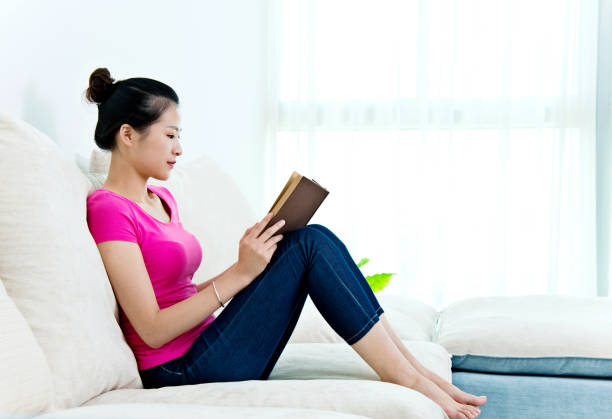 Beautiful young woman reading a book at home