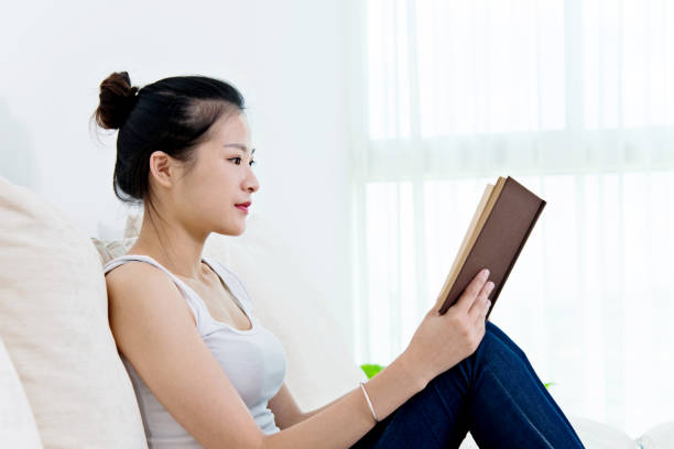 istock Beautiful young woman reading a book at home 694848794