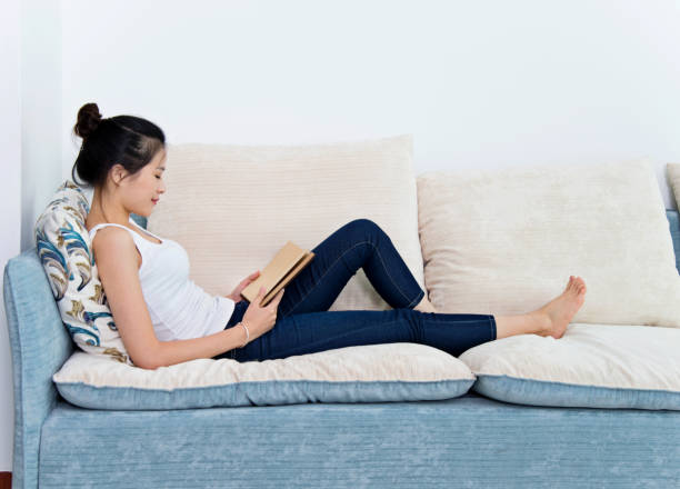 istock Beautiful young woman reading a book at home 694848898