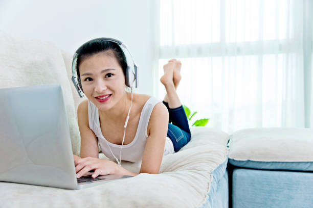 One woman, sitting on bedroom floor, listening music on headphones.