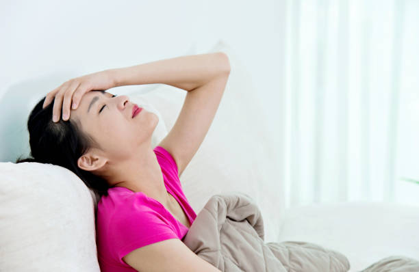 istock Young asian woman in a couch with headache 694852470