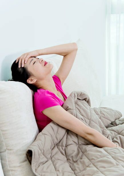 istock Young asian woman in a couch with headache 694852570
