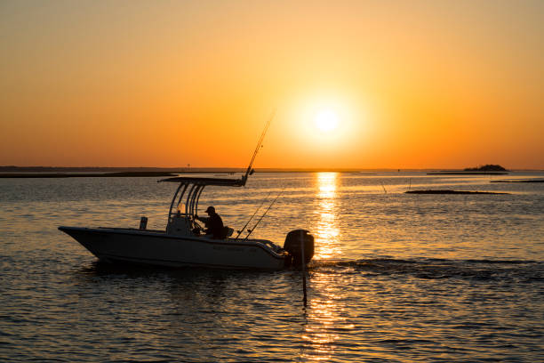 Sunrise fishing trip Emerald Isle, NC - May 27, 2017: A fisherman is riding his boat through intracoastal water while the sun is rising. emerald isle north carolina stock pictures, royalty-free photos & images
