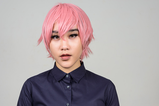 Disparo de estudio de jóvenes transgénero Asia adolescente con cabello rosado contra el fondo gris photo