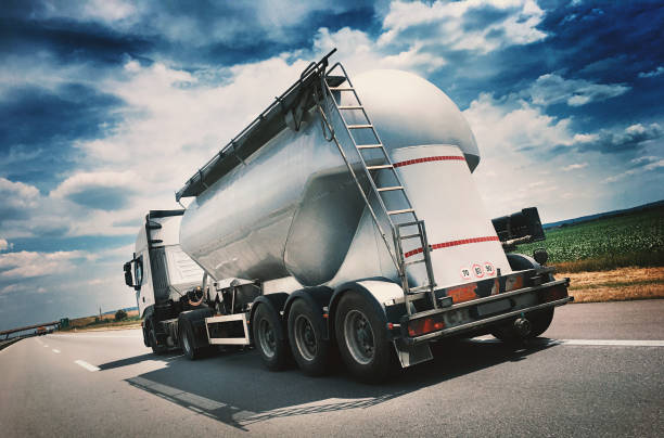 Heavy Cargo on the Road Closeup rear view of a white tanker truck driving on a highway. It's sunny summer day and the road is clear. Toned image. gas tank photos stock pictures, royalty-free photos & images
