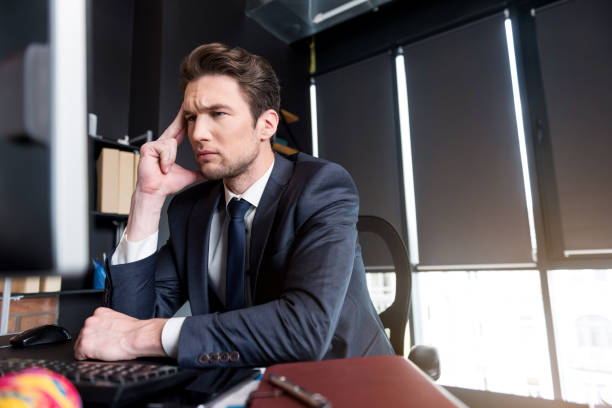 istock Pensive young man with headache sitting in office 694924676