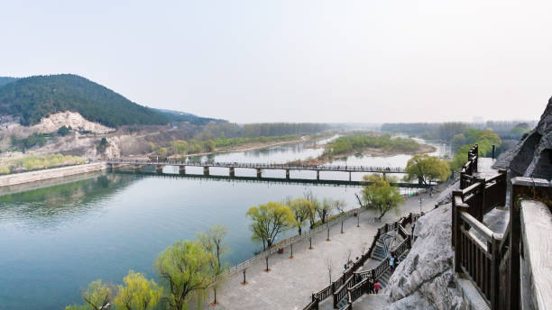 view with Bridge on Yi river and Longmen Grottoes travel to China - panoramic view with Manshui Bridge on Yi river and Longmen Grottoes area in spring season mikuni pass stock pictures, royalty-free photos & images