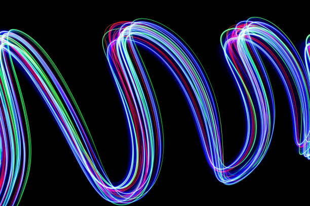 istock Multi-coloured light painting photography in a rolling, wavy pattern, against a black background 694928198