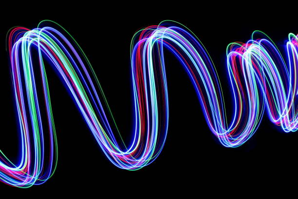 istock Multi-coloured light painting photography in a rolling, wavy pattern, against a black background 694928274