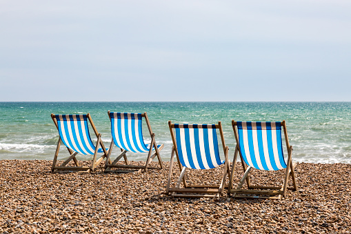 A photograph of four empty deck chairs on the beach at Brighton, UK.
