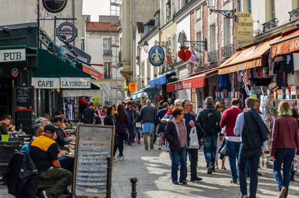 A typical lively weekend street scene in Paris. This photo taken in the Montmarte district contains numerous shops, cafes, and restaurants with their patrons.