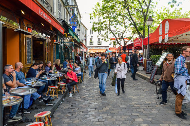 A typical lively weekend street scene in Paris. This photo taken in the Montmarte district contains numerous shops, cafes, and restaurants with their patrons.