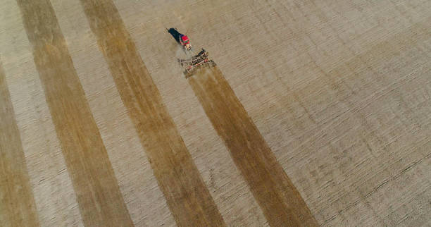 istock Springtime agricultural activity, red tractor cultivating field 694944384