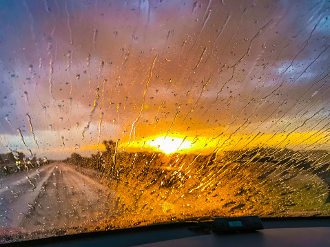 Life is a highway beckoning one forward. Breathtaking sunrise as seen through rainy windshield.
