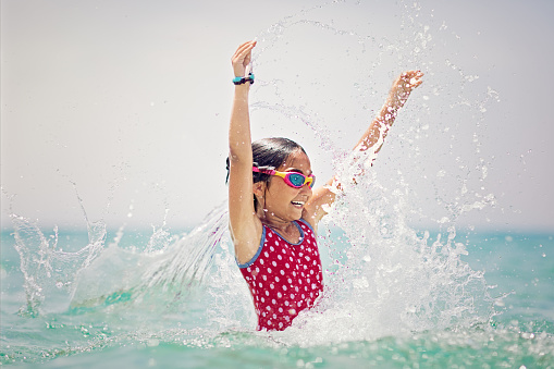 Little girl is jumping and playing in the ocean