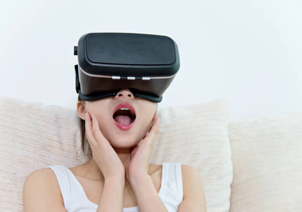 istock Young woman using VR headset at home 694982862