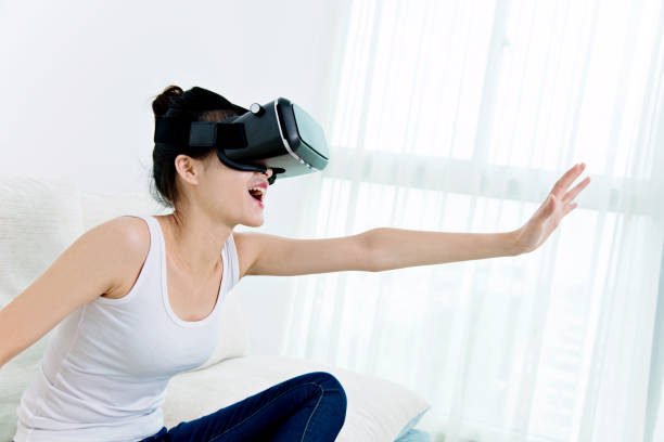 istock Young woman using VR headset at home 694982900