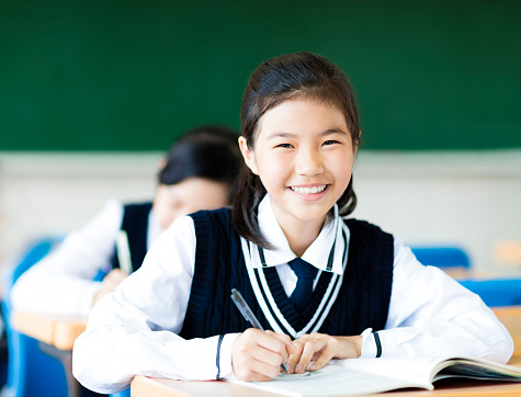 smiling student girl in classroom and her friends in background