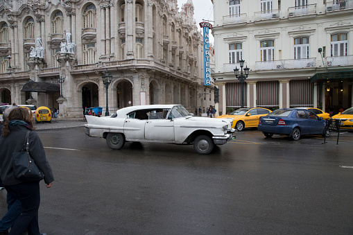 Havana, Cuba - January 29, 2017:Antique car driving  on a rainning day. Incidental people on the background.