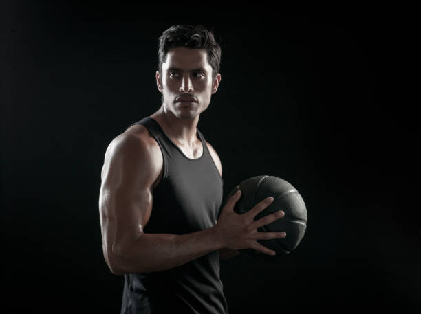 istock Man Holding a Basketball On A Black Background 695012728