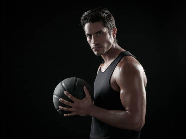 istock Man Holding a Basketball On A Black Background 695012798