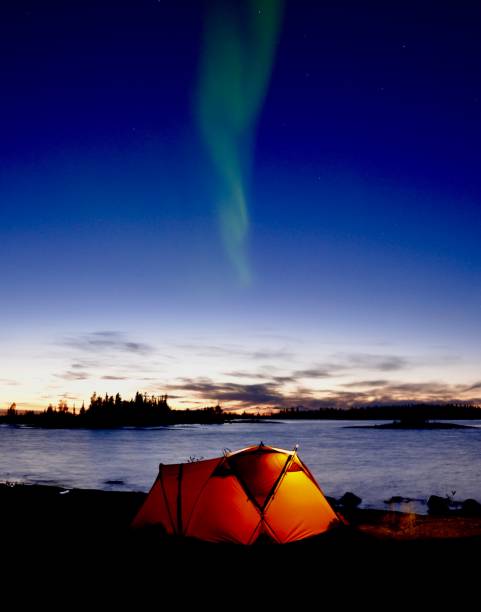 Aurora Plume The Aurora Borealis shining strong above a glowing tent. great slave lake stock pictures, royalty-free photos & images