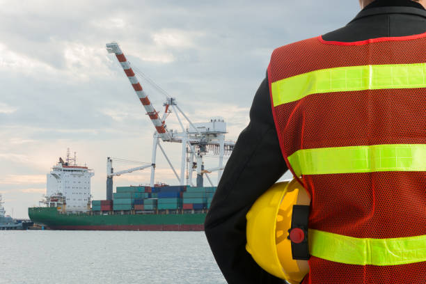 istock Hand or arm of engineer hold yellow plastic helmet in front of cargo 695052436