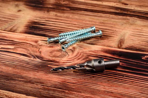 Drill bit and confirmats on wooden table Drill bit and confirmats on rustic wooden table boreray and stac lee stock pictures, royalty-free photos & images