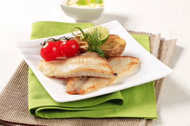 Skinless fish fillets with baked potato half Pan fried fish fillets with roasted potato hake stock pictures, royalty-free photos & images