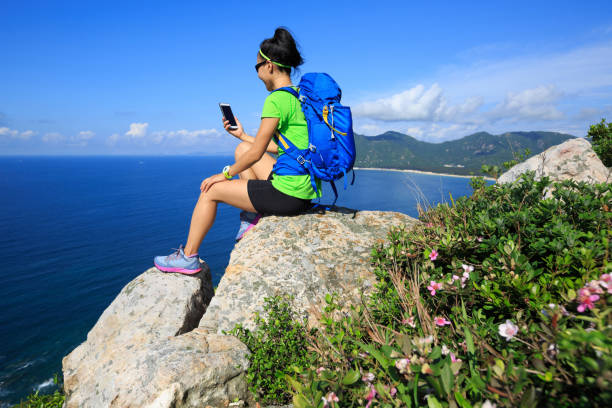 istock successful woman backpacker use smartphone on seaside mountain rock 695110994