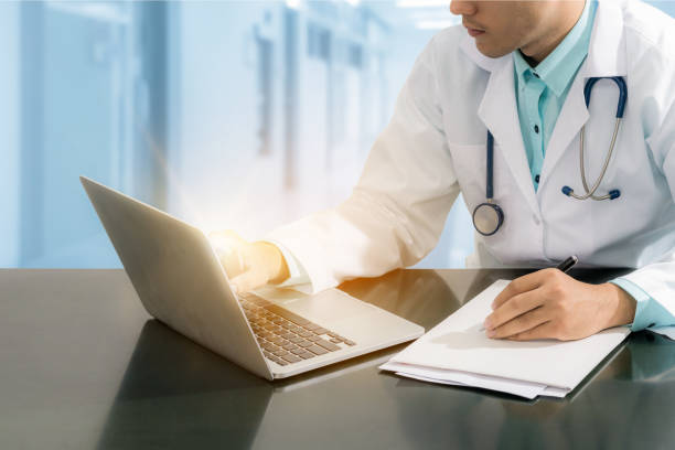 istock Doctor working on desk with laptop 695120714