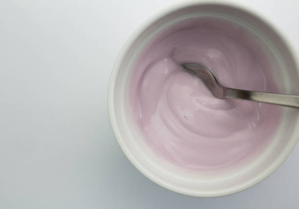 istock Healthy raspberry fruit flavored yoghurt with natural coloring in glass bowl isolated on white background with spoon - top view 695123774