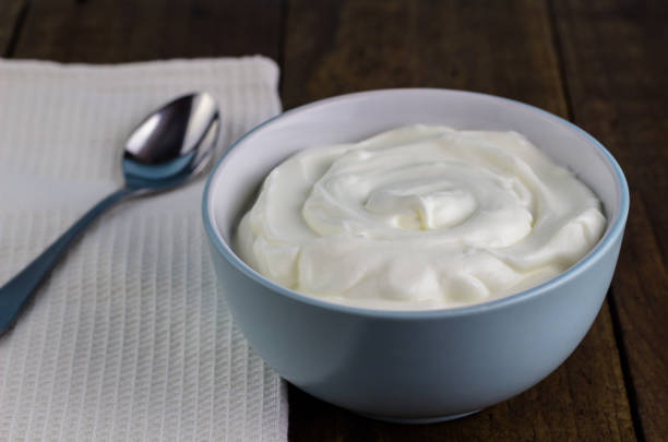 istock Natural yoghurt in bowl with spoon on rustic wooden table background 695123920