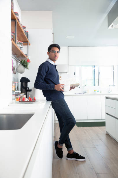 istock Young indian man reading in the kitchen 695130172