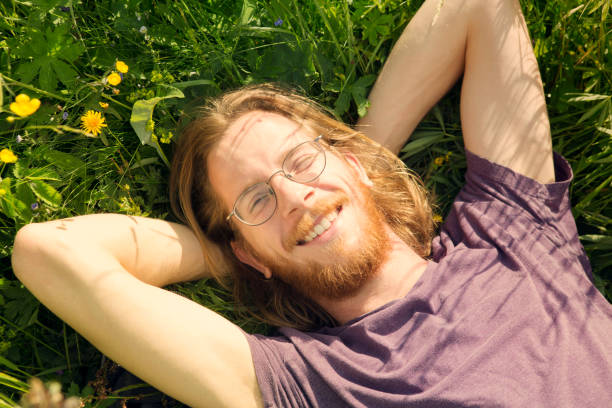 istock young red-haired man lying in grass and smiling 695134956
