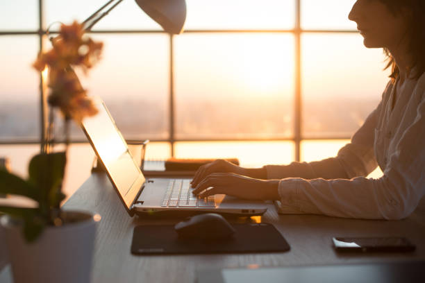 istock Side view photo of a female programmer using laptop, working, typing, surfing the internet at workplace. 695137252