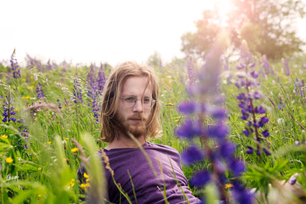 istock handsome young man sitting in a flower field 695137330