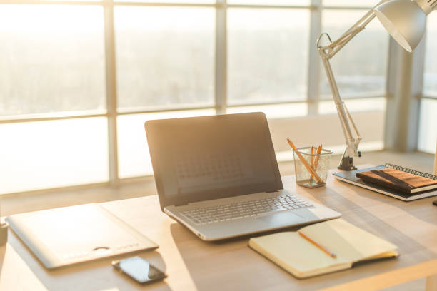 Side view picture of studio workplace with blank notebook, laptop. Comfortable work table, home office.