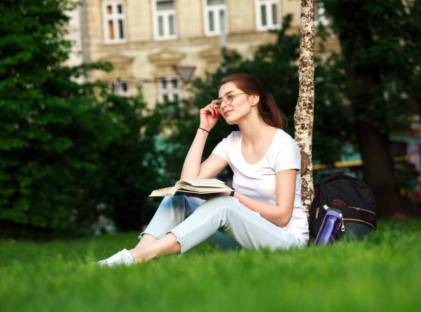 istock Smiling girl student in city park with book 695140866