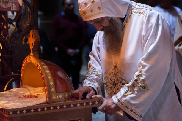 Jerusalem, Israel - November 10, 2016: Coptic priest in a Coptic Chapel at the back of the Rotunda in Holy Sepulchre during Sunday Holy Mass. Coptic Church is one of 6 Christian denominations present in the Church. All privileges and duties, such as the m Jerusalem, Israel - November 10, 2016: Coptic priest in a Coptic Chapel at the back of the Rotunda in Holy Sepulchre during Sunday Holy Mass. Coptic Church is one of 6 Christian denominations present in the Church. All privileges and duties, such as the mass, of all Christian denominations present in the Church are arranged by over 160 years old rules and regulation decree - so called Status Quo. east jerusalem stock pictures, royalty-free photos & images
