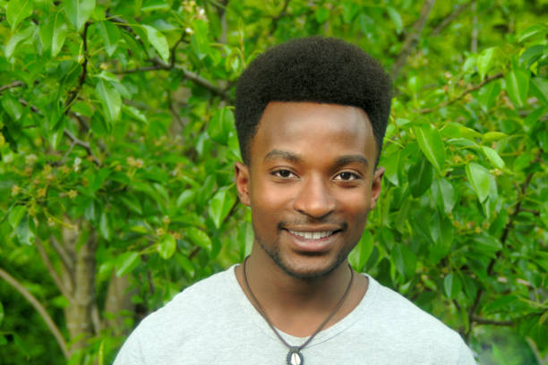 istock young african man outside tree backgound portrait smiling 695148576