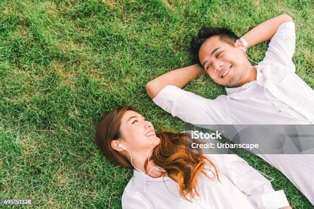 Young Asian Lovely Couple Or College Students Lying Down On The Grass Together Listening To Music Top View With Copy Space Love Relationship Wedding Or Relaxing Casual Lifestyle Concept Stock Photo - Download Image Now