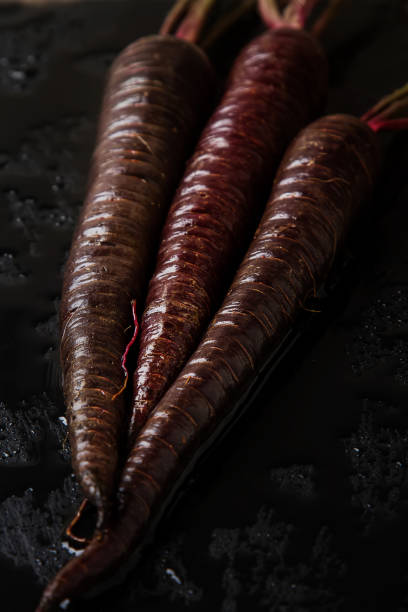 Ripe black carrots. Dark stone background. Autumn harvest. Top view