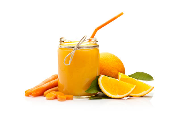 Front view of a glass jar with orange and carrot juice shot on reflective white background. Orange fruits and carrots are beside the jar. Predominant colors are orange and white. DSRL studio photo taken with Canon EOS 5D Mk II and Canon EF 100mm f/2.8L Macro IS USM