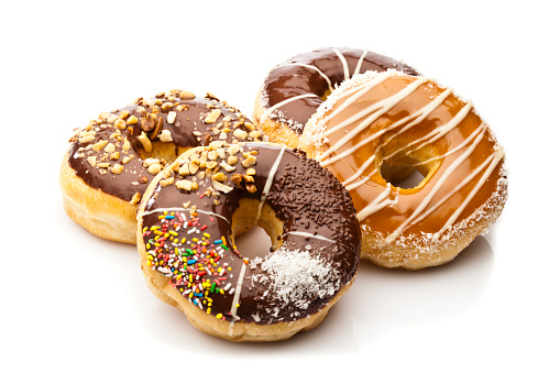 Pile of four glazed donuts isolated on reflective white background. Predominant colors are brown and white. DSRL studio photo taken with Canon EOS 5D Mk II and Canon EF 70-200mm f/2.8L IS II USM Telephoto Zoom Lens