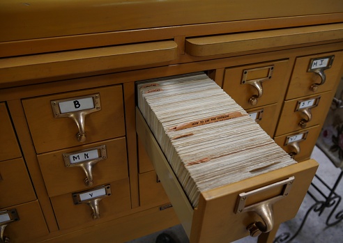 A sturdy wooden cabinet containing index cards of a library cataloguing system