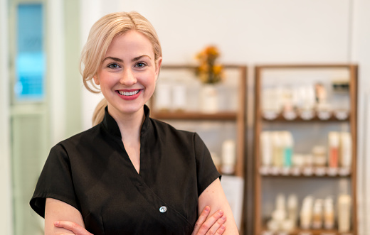 Portrait of a happy business owner working at a spa selling products and looking at the camera smiling - beauty concepts