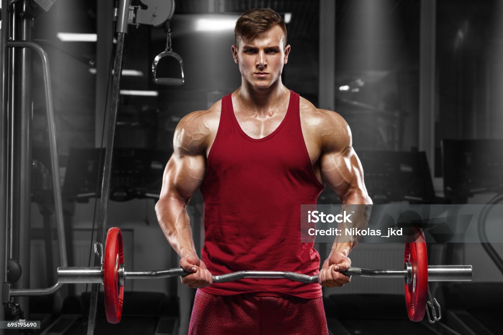 Muscular man working out in gym doing exercises with barbell, strong male Abdomen Stock Photo